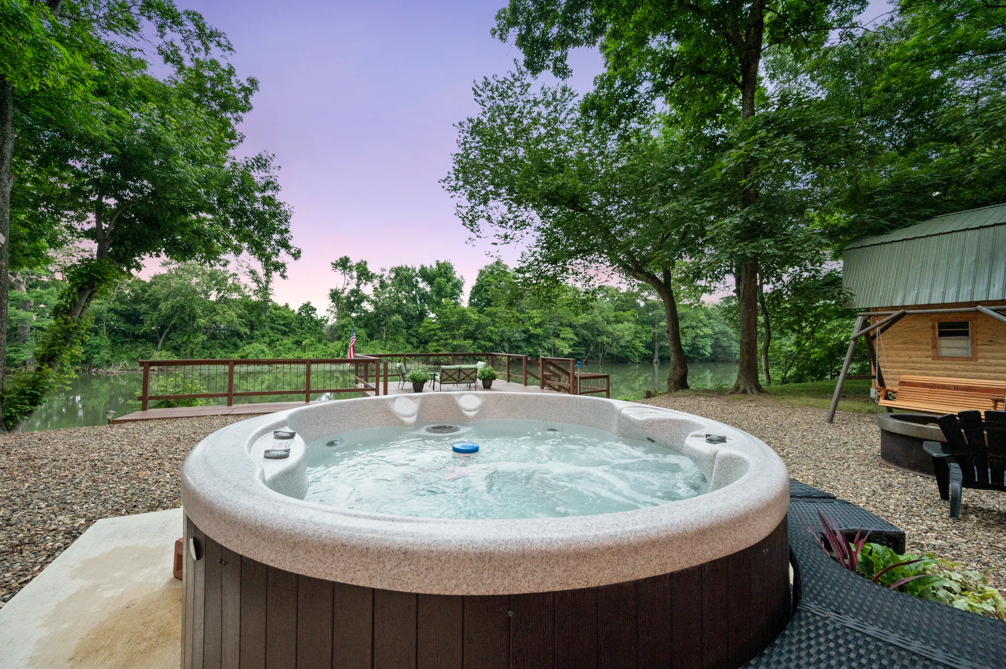 The hot tub sits between the cabin and the fire pit.