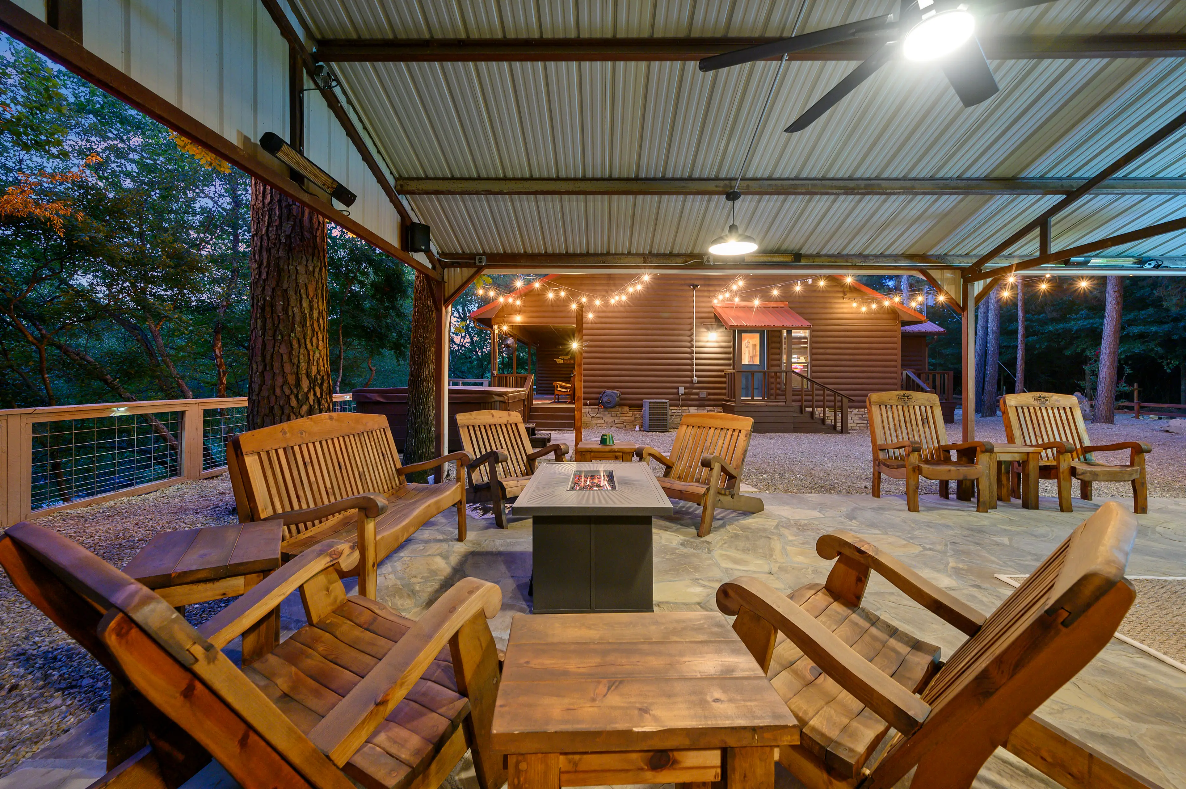The outside living area is separated from the cabin with string lights over the hot tub.