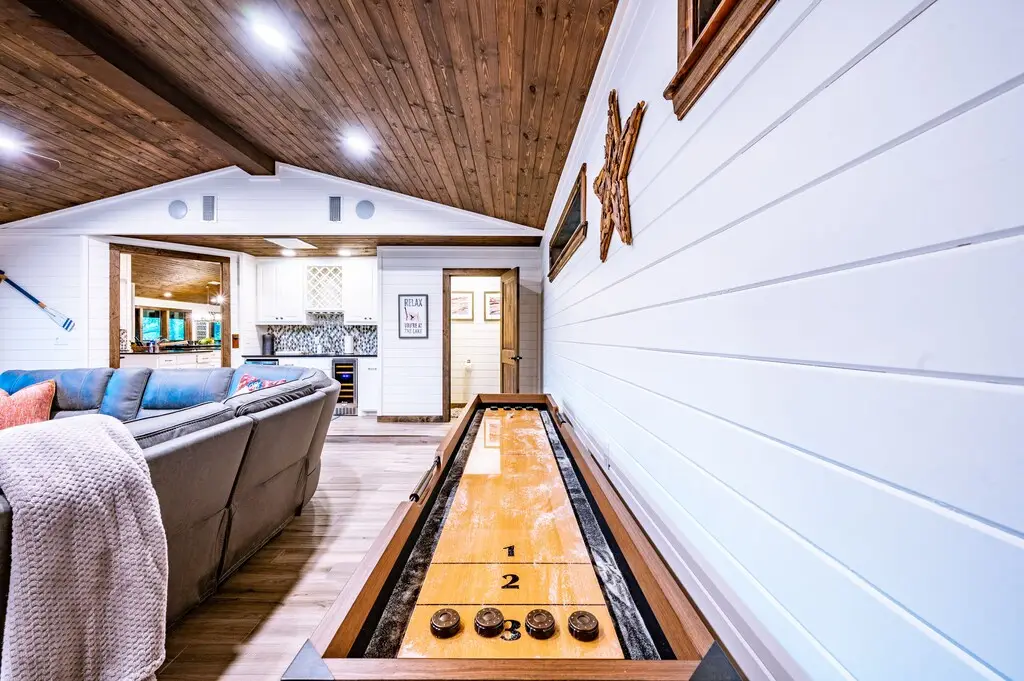 Game room has a shuffle board, huge sectional, bar area, and a half bath.